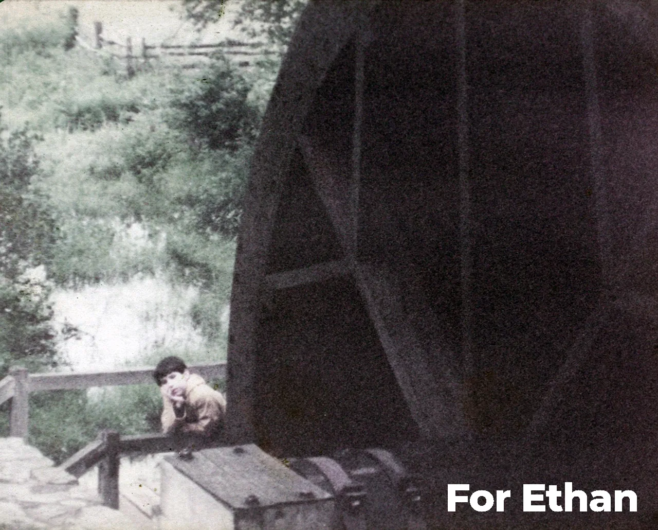 Picture of Ethan Clow as a child in front of a water wheel